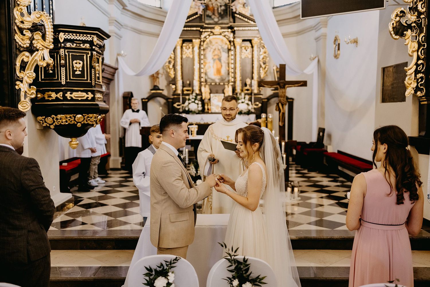 Bride and groom exchanging vows at the altar of an ornate Catholic church.