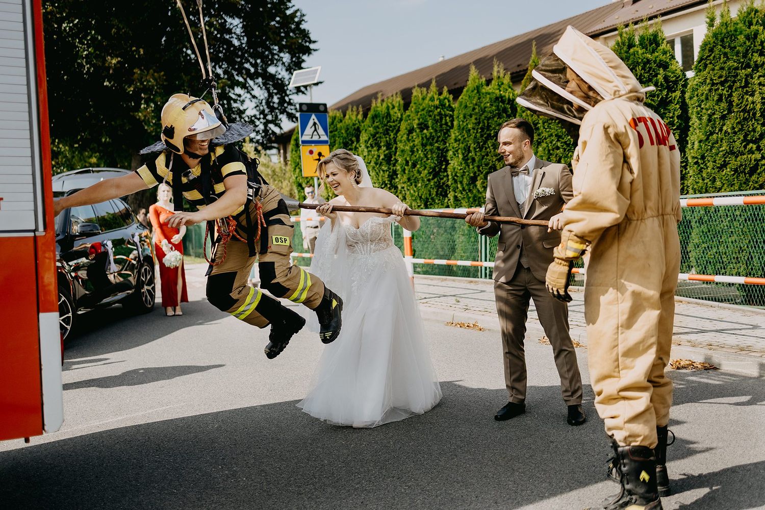 Bride and groom posing with firefighters in full gear beside a fire truck at a unique wedding celebration.