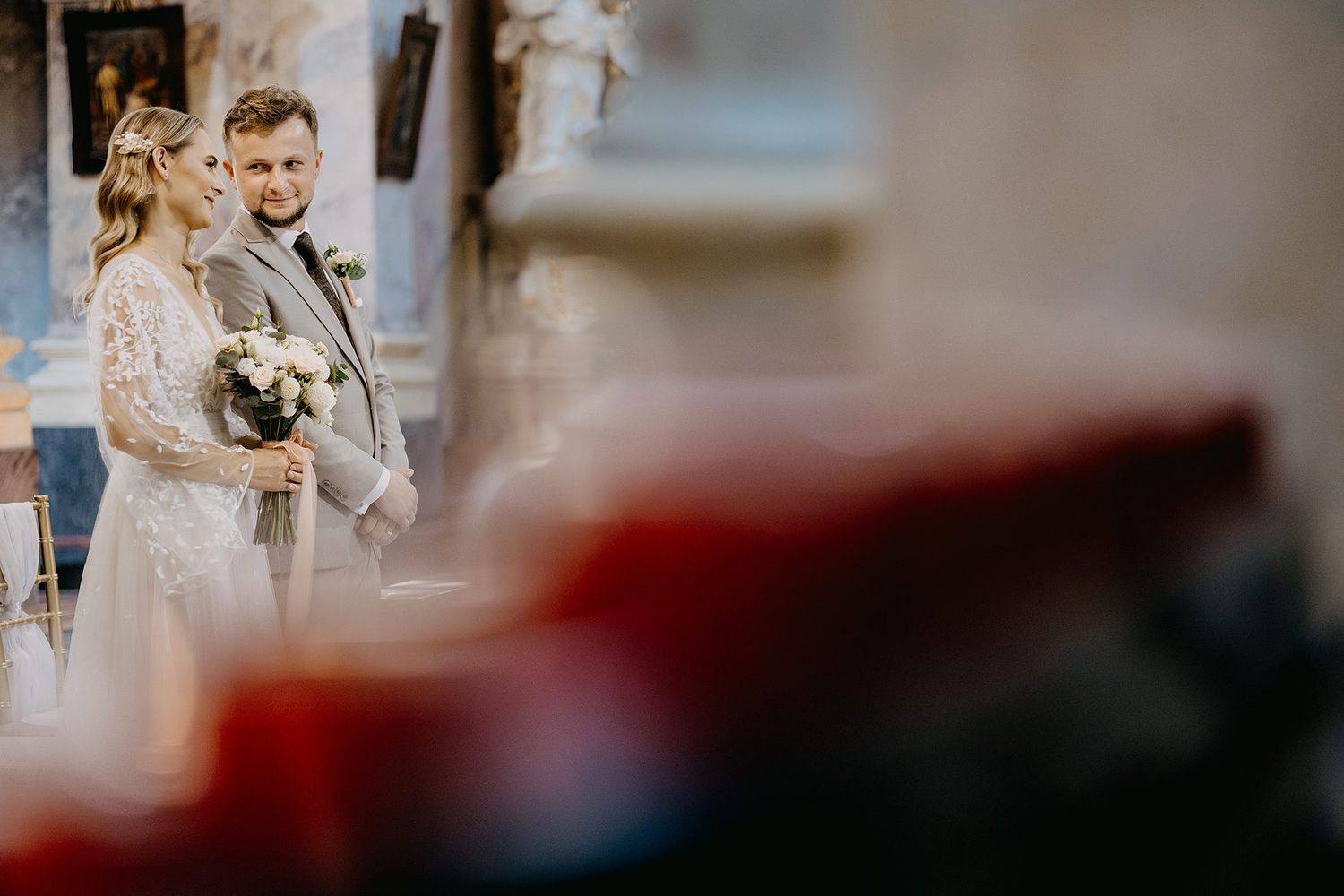 Bride and groom standing together at the altar inside an ornate church during ceremony.
