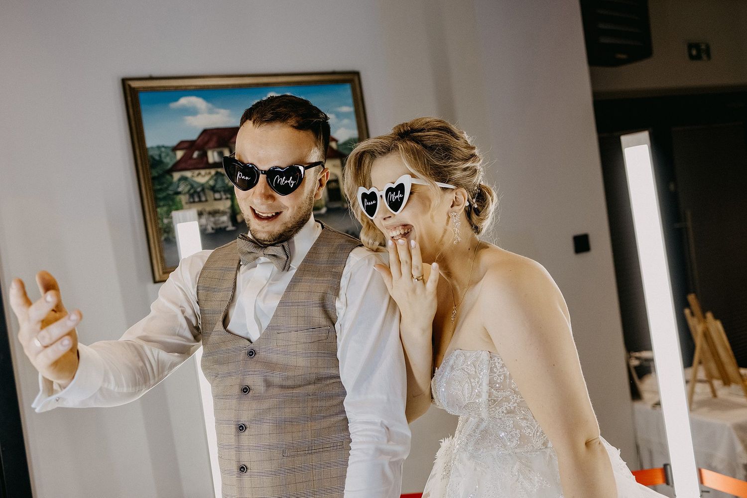Bride and groom wearing fun heart-shaped sunglasses taking a selfie together at their wedding reception.