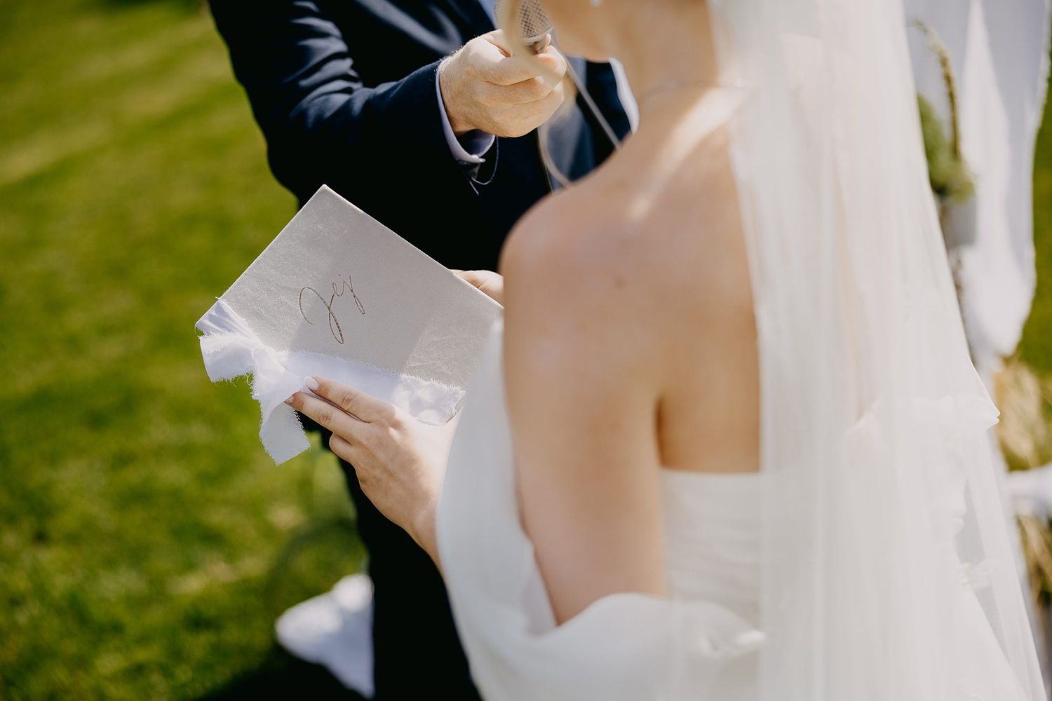 Officiant reads vows from paper while bride in white gown and veil listens.