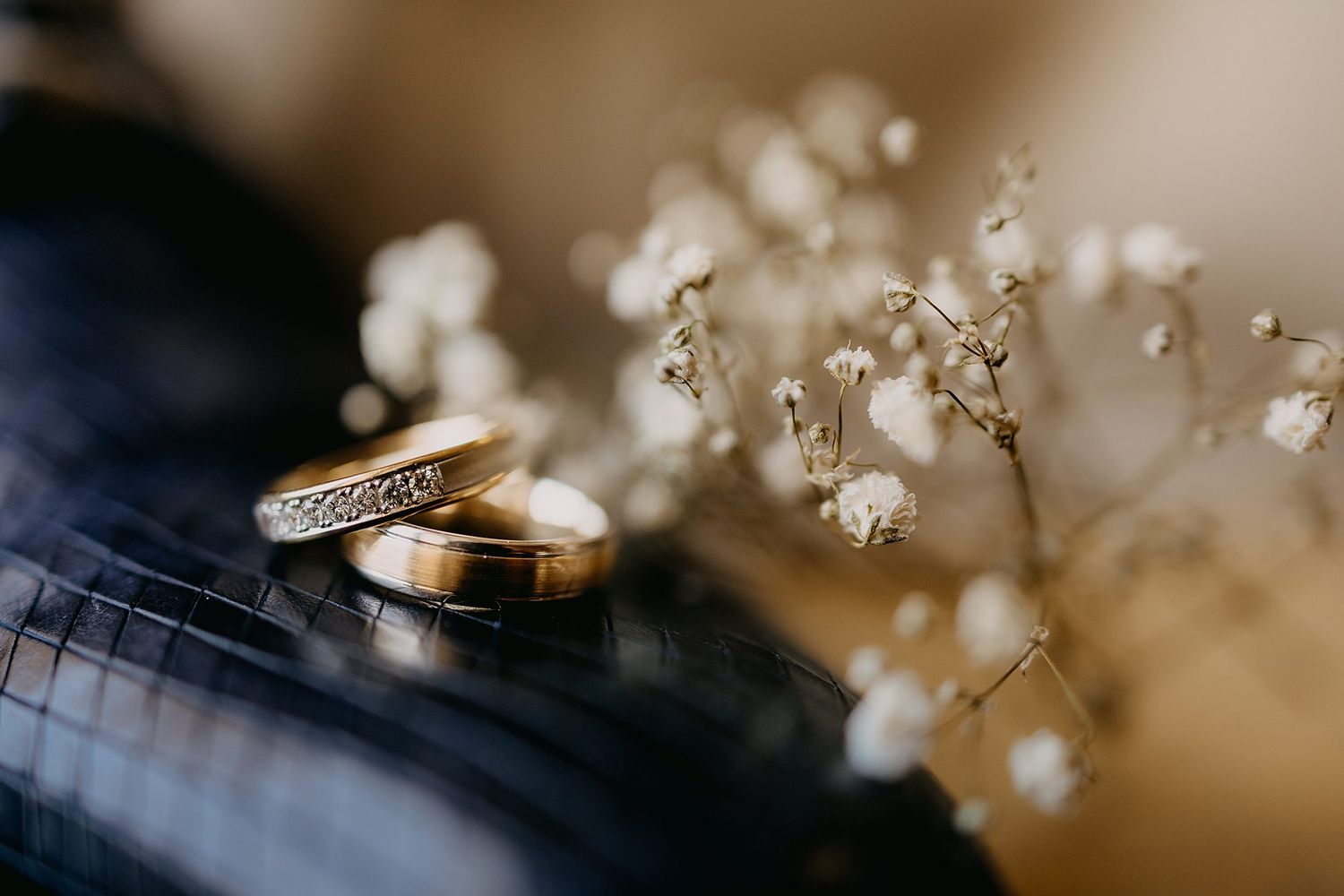 Two gold wedding rings resting near delicate white baby breath flowers.