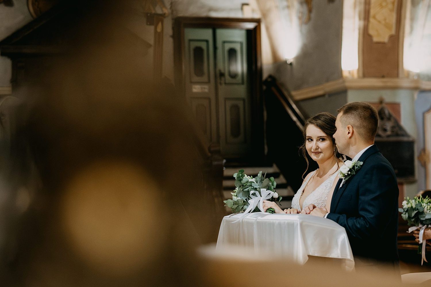 Bride and groom exchanging vows at intimate church ceremony altar.