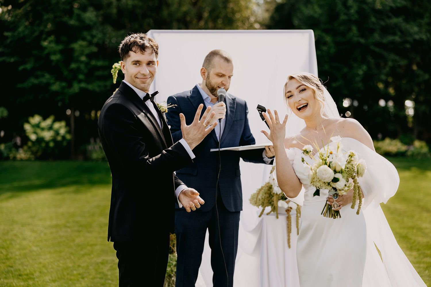 Bride and groom exchange vows outdoors with officiant during elegant garden wedding ceremony.