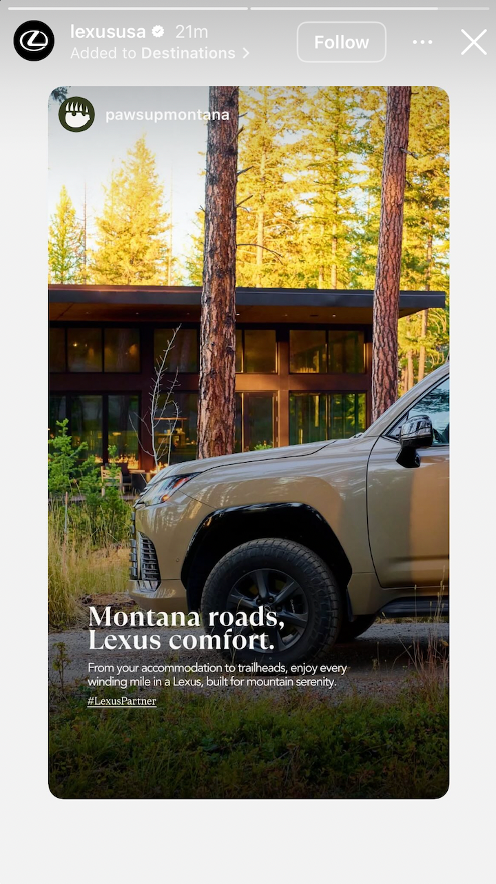 Tan Lexus SUV parked near a modern Montana lodge with tall pine trees in warm sunlight.
