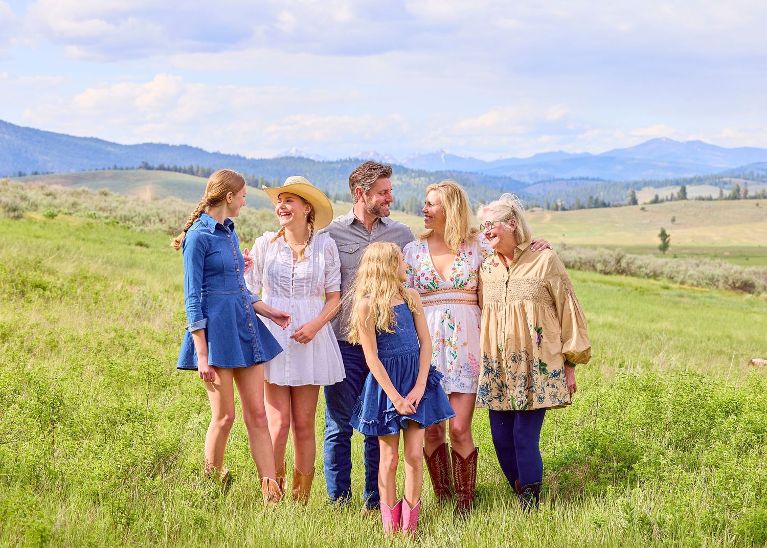 Extended multigenerational family posing together in green meadow with Rocky Mountain backdrop.