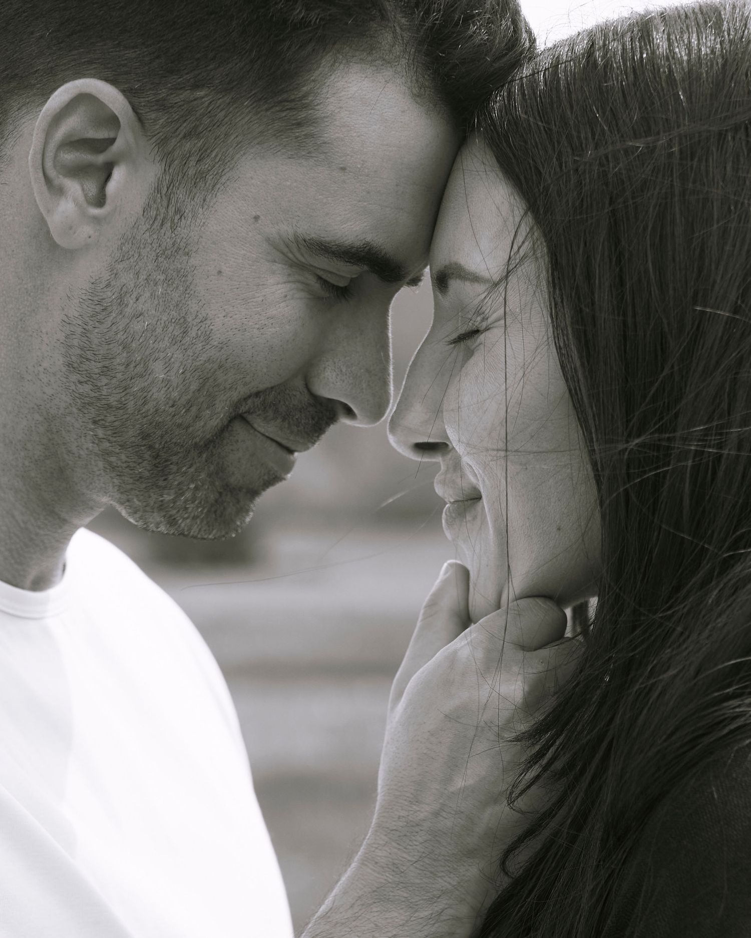 Black and white close-up of romantic couple touching foreheads tenderly.