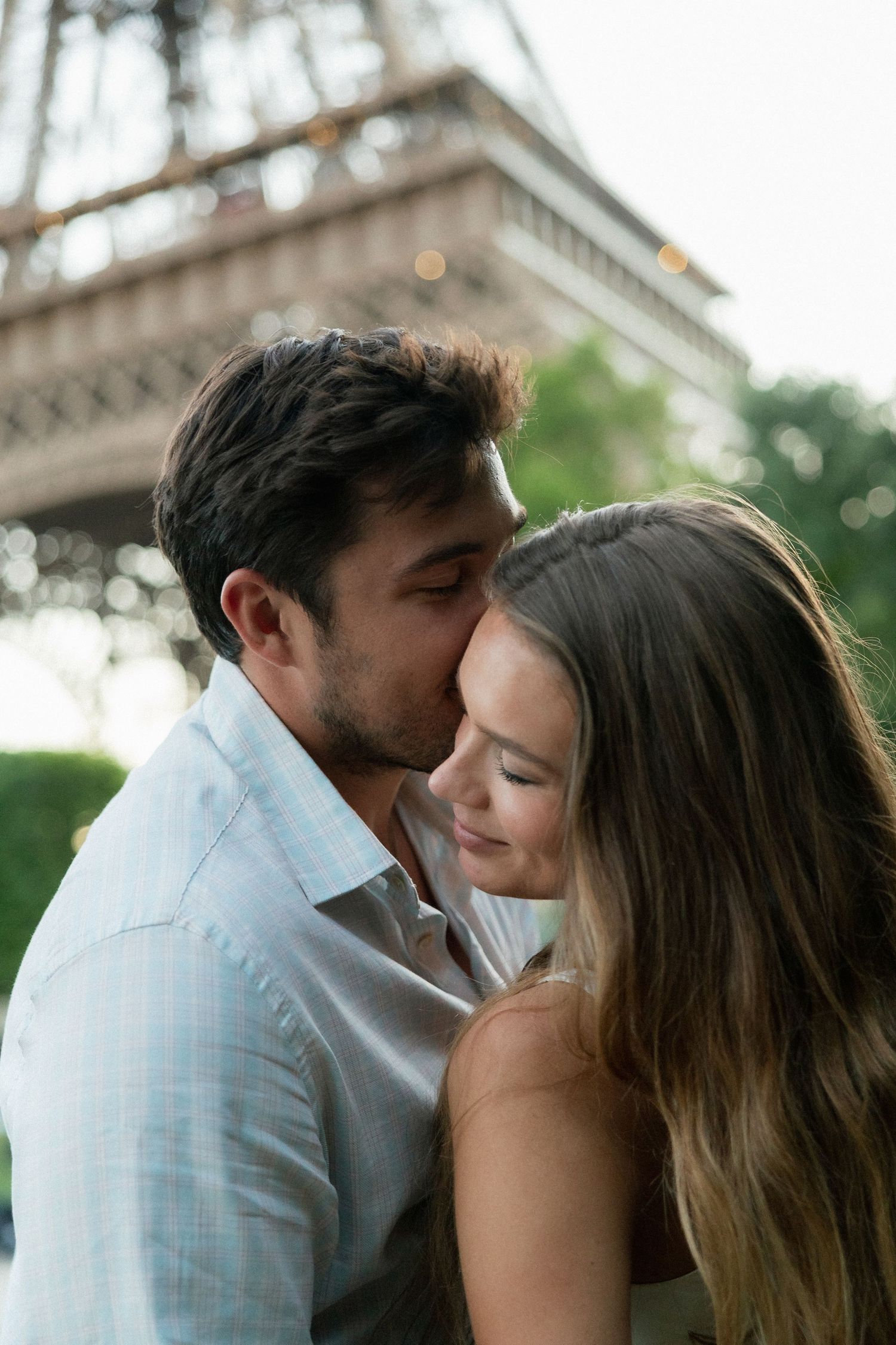 A romantic couple shares a tender kiss in front of the Eiffel Tower in Paris, France.