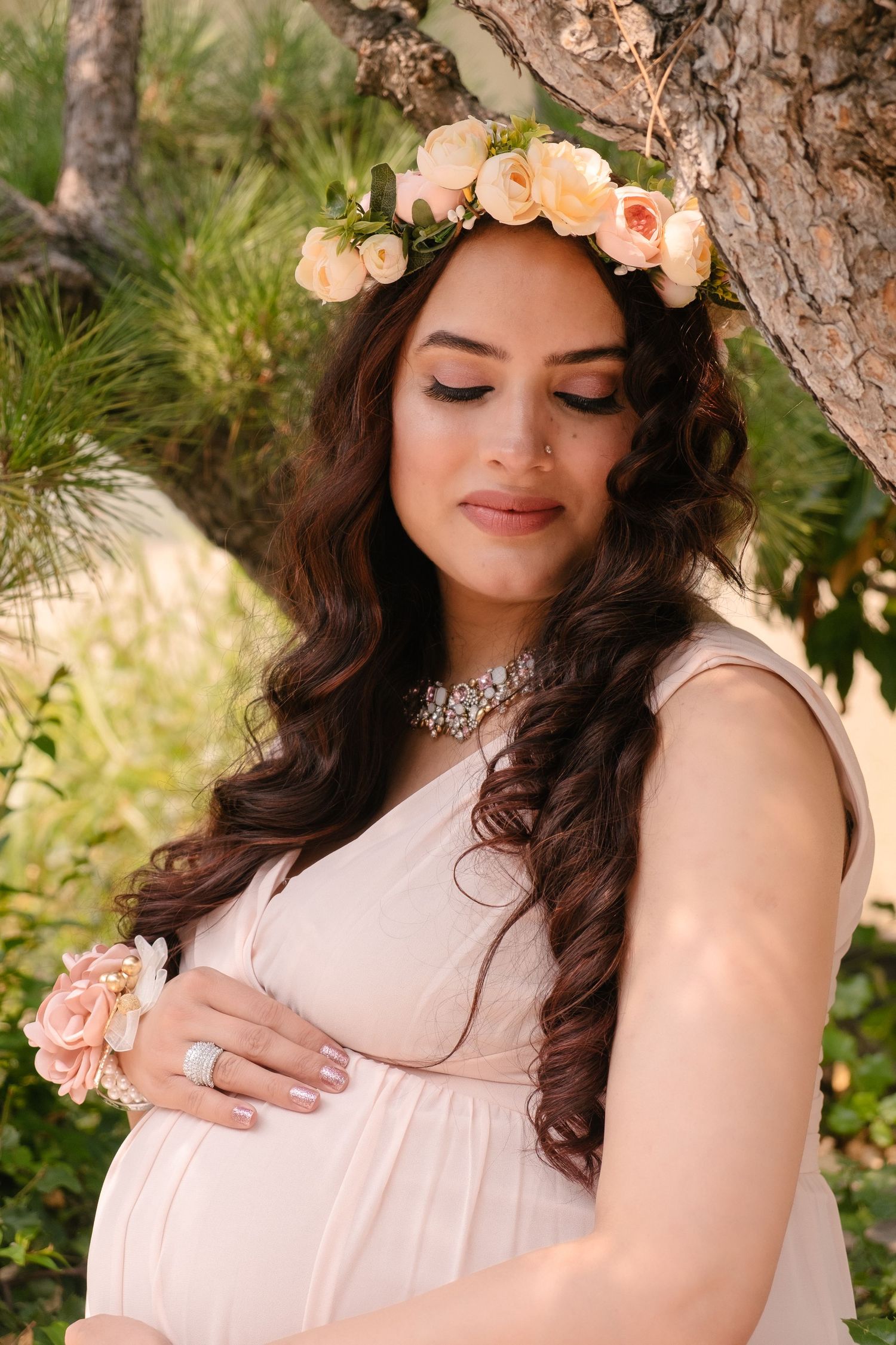 Radiant maternity portrait in a Hayward Japanese garden featuring a mother in a peach dress and floral crown