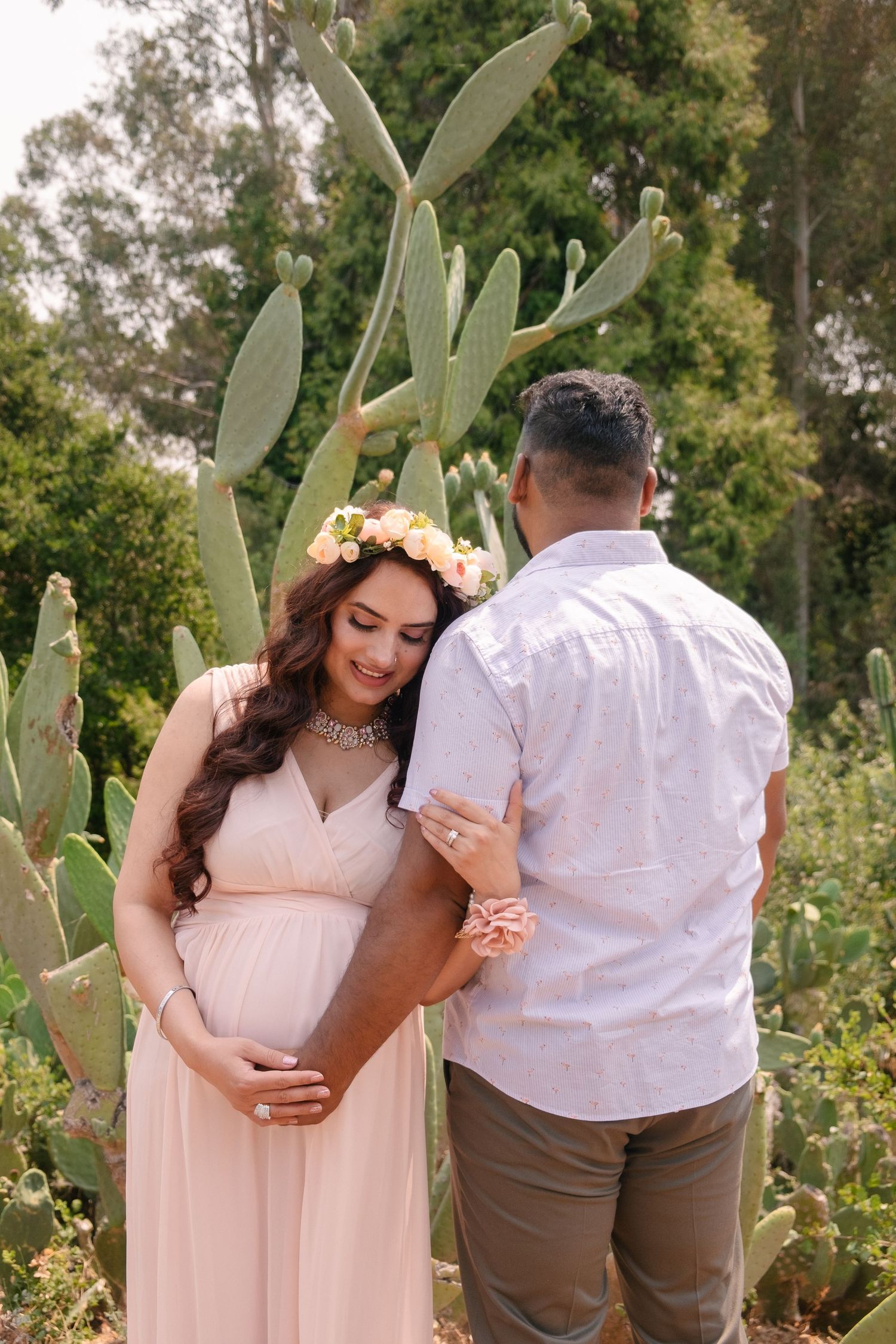 Maternity portrait in a Hayward Japanese garden featuring a mother in a peach dress and father holding each others arms