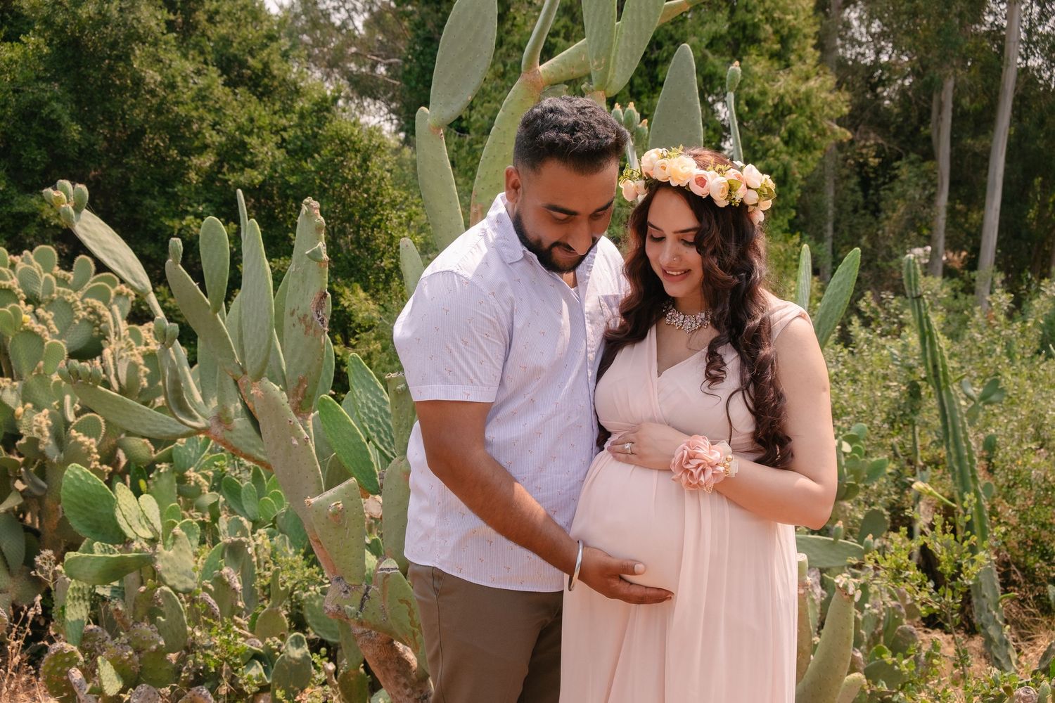 Maternity portrait in a Hayward Japanese garden featuring a mother in a peach dress and father holding each others arms