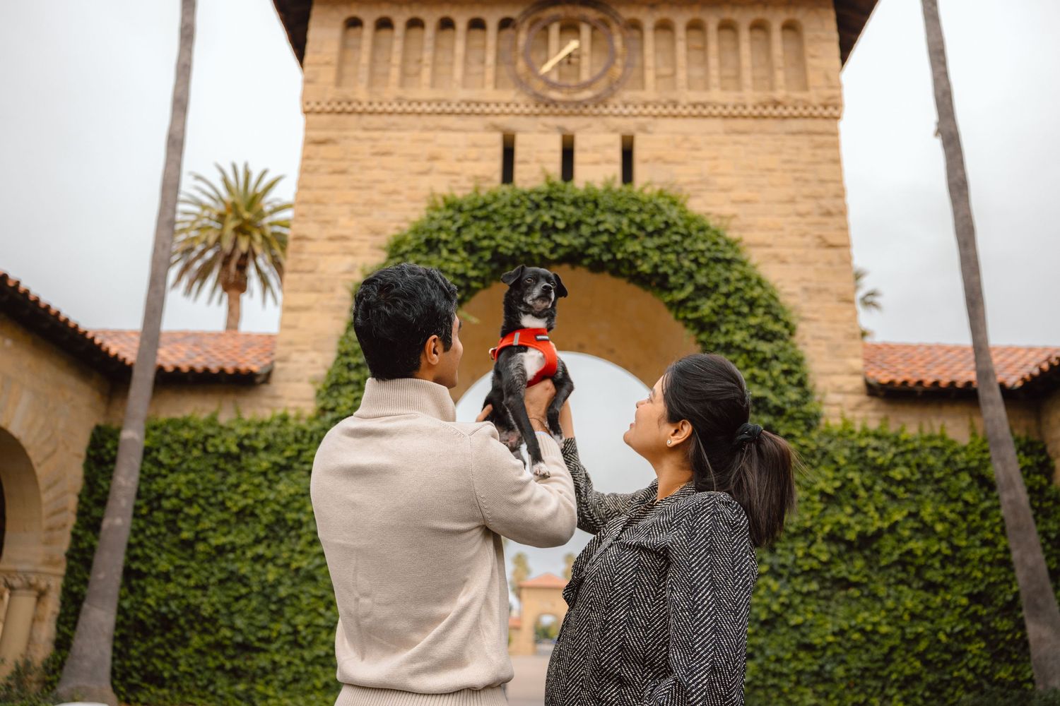 dad holding their pup with mom with arch background in Stanford University