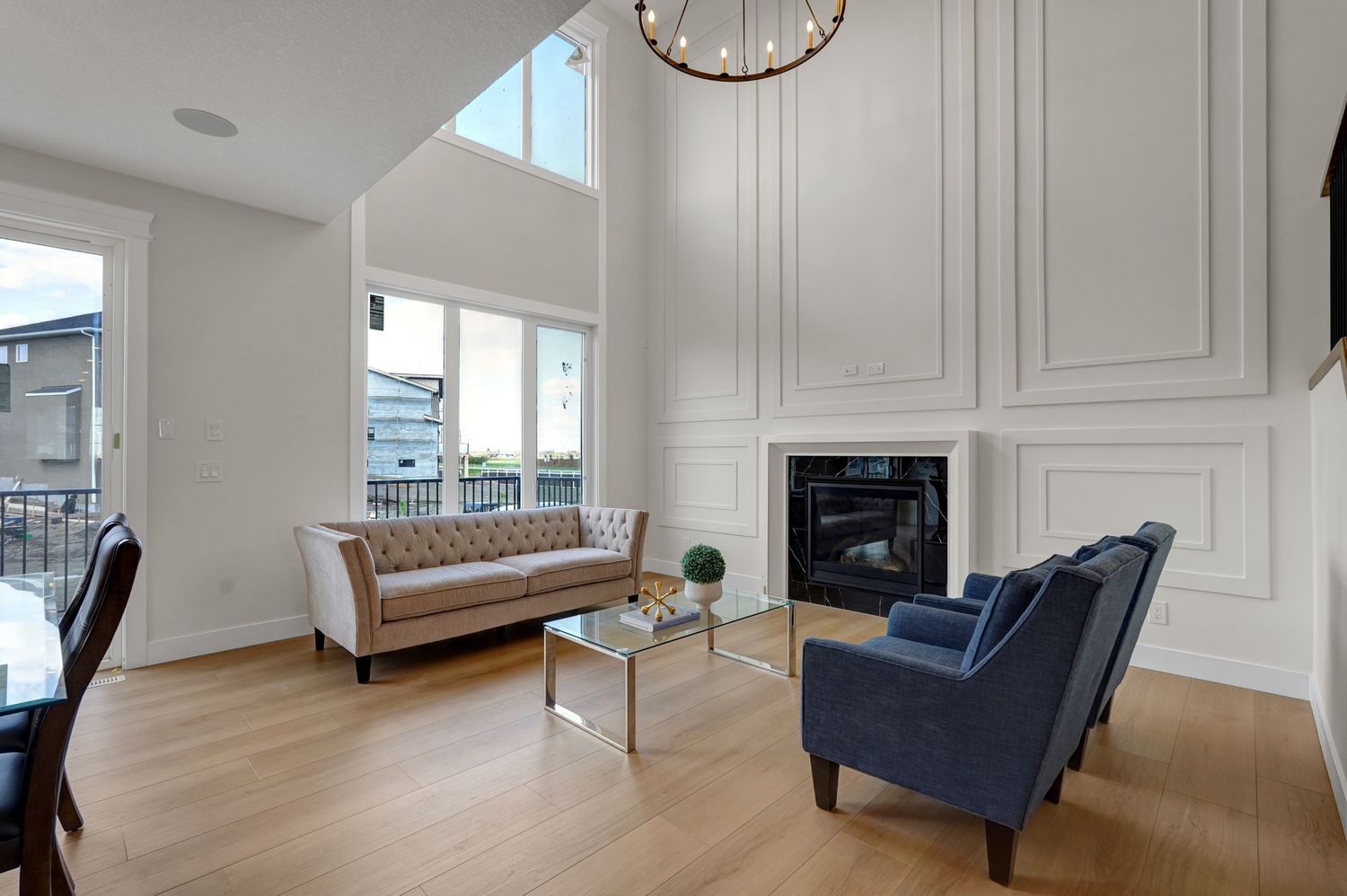 Bright living room with vaulted ceiling, wainscoting, fireplace, and large windows.