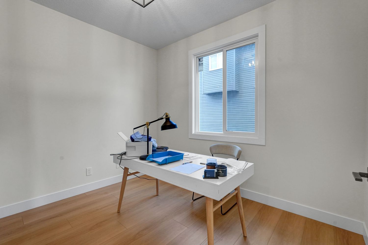 Minimalist home office with wooden desk, task lamp, and hardwood flooring.