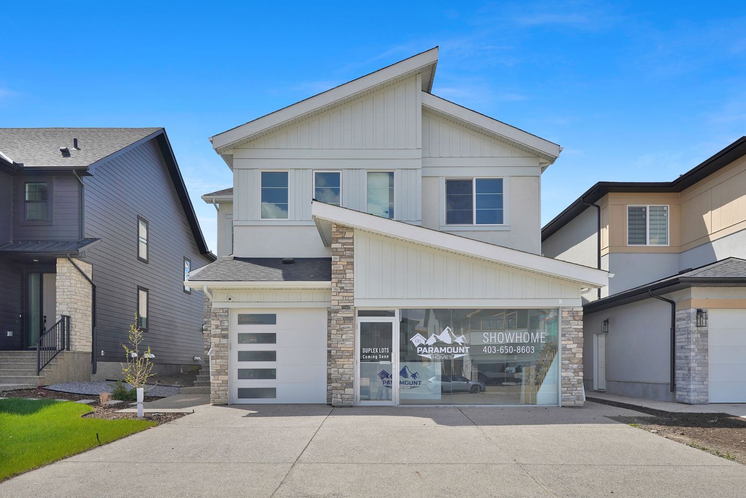 Modern two-story home exterior with board and batten siding, stone accents, and double garage door.