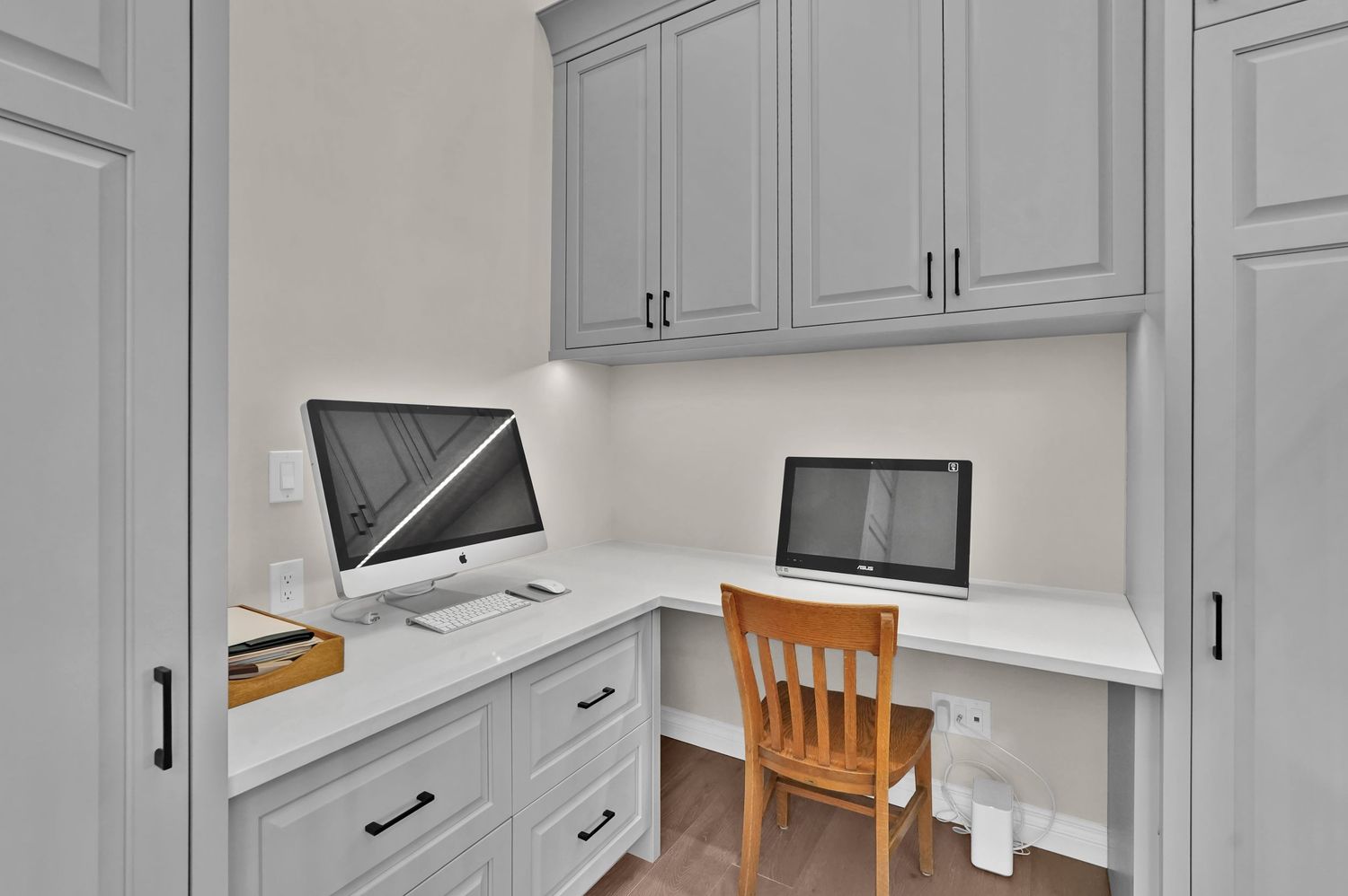 Built-in home office nook with gray cabinets, white quartz desk, iMac computer, and wooden chair.