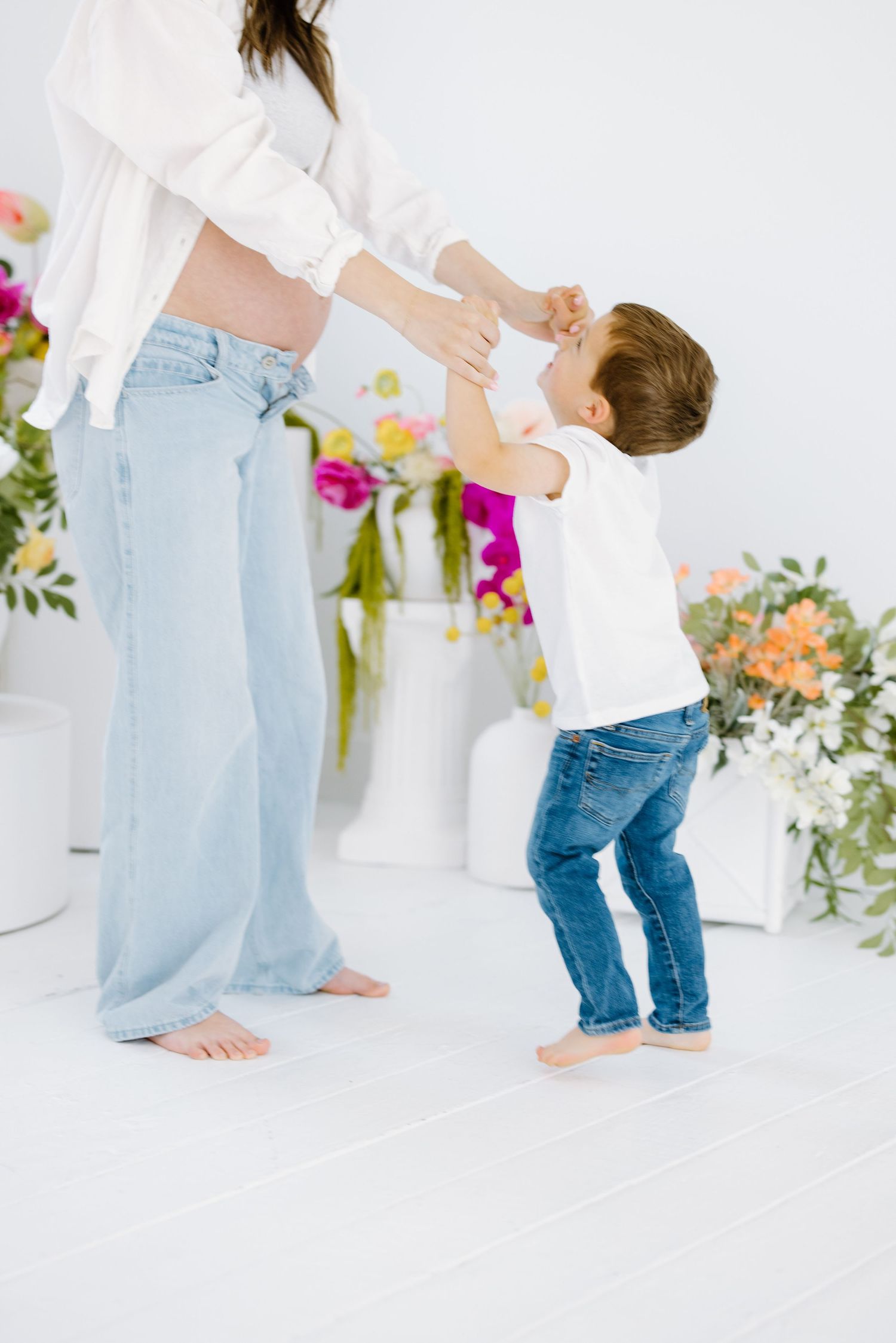 A playful scene shows a dance-like interaction against a backdrop of colorful floral arrangements in a bright white setting.