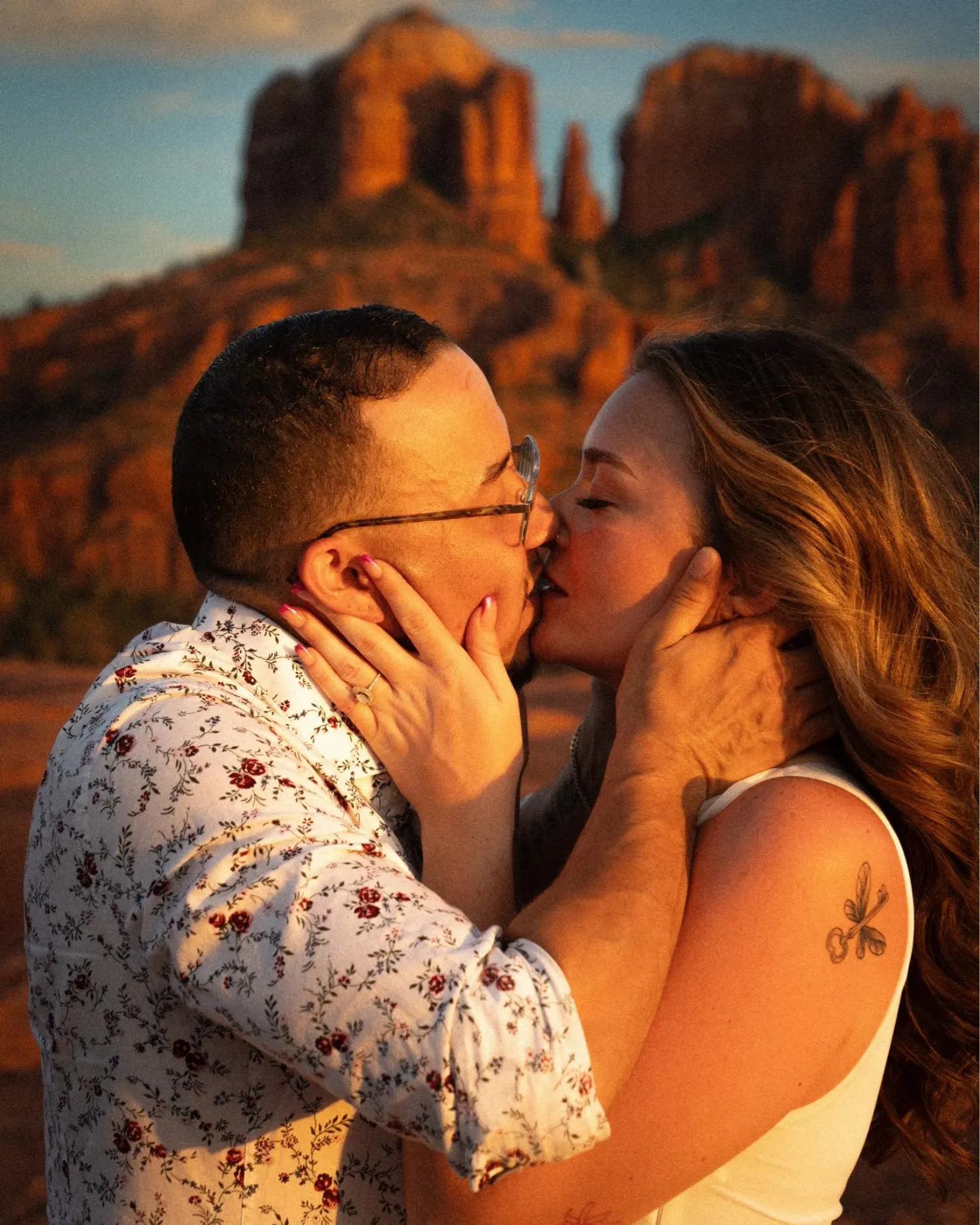 Couple sharing an intimate moment against dramatic red rock formations at sunset.