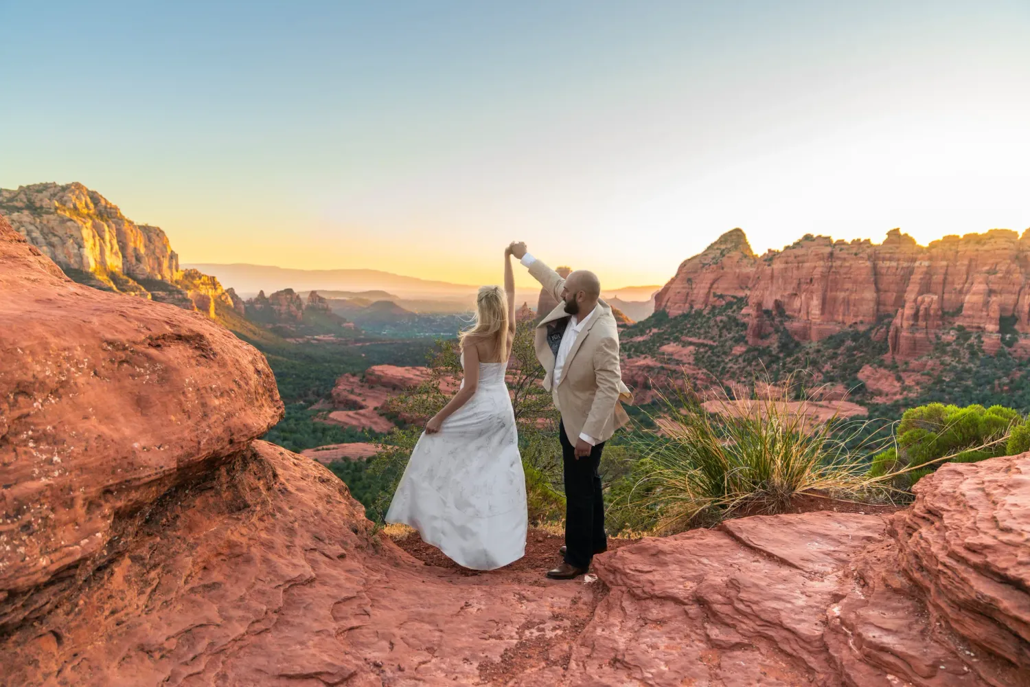Bride and groom at Merry Go Round Rock overlooking panoramic red rock views in Sedona, Arizona.