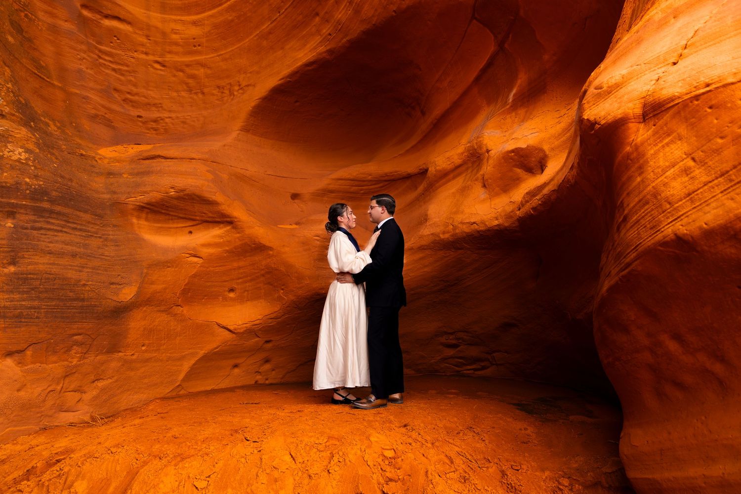 Light beams filtering through curved sandstone walls in Antelope Canyon for a happy bride and groom.