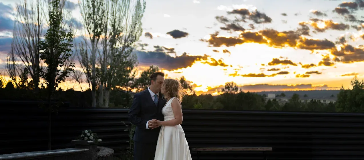 Sunset silhouettes tall trees against a vibrant orange and purple sky in a scenic landscape with a bride and groom in Flagstaff, Arizona.
