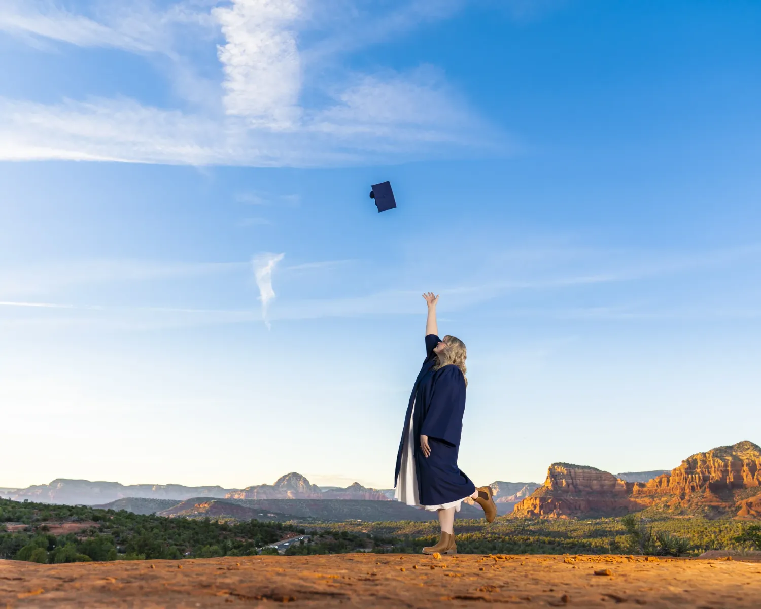 Senior girl throwing her graduation cap with Bell Rock and Sedona red rock landscape in the background.