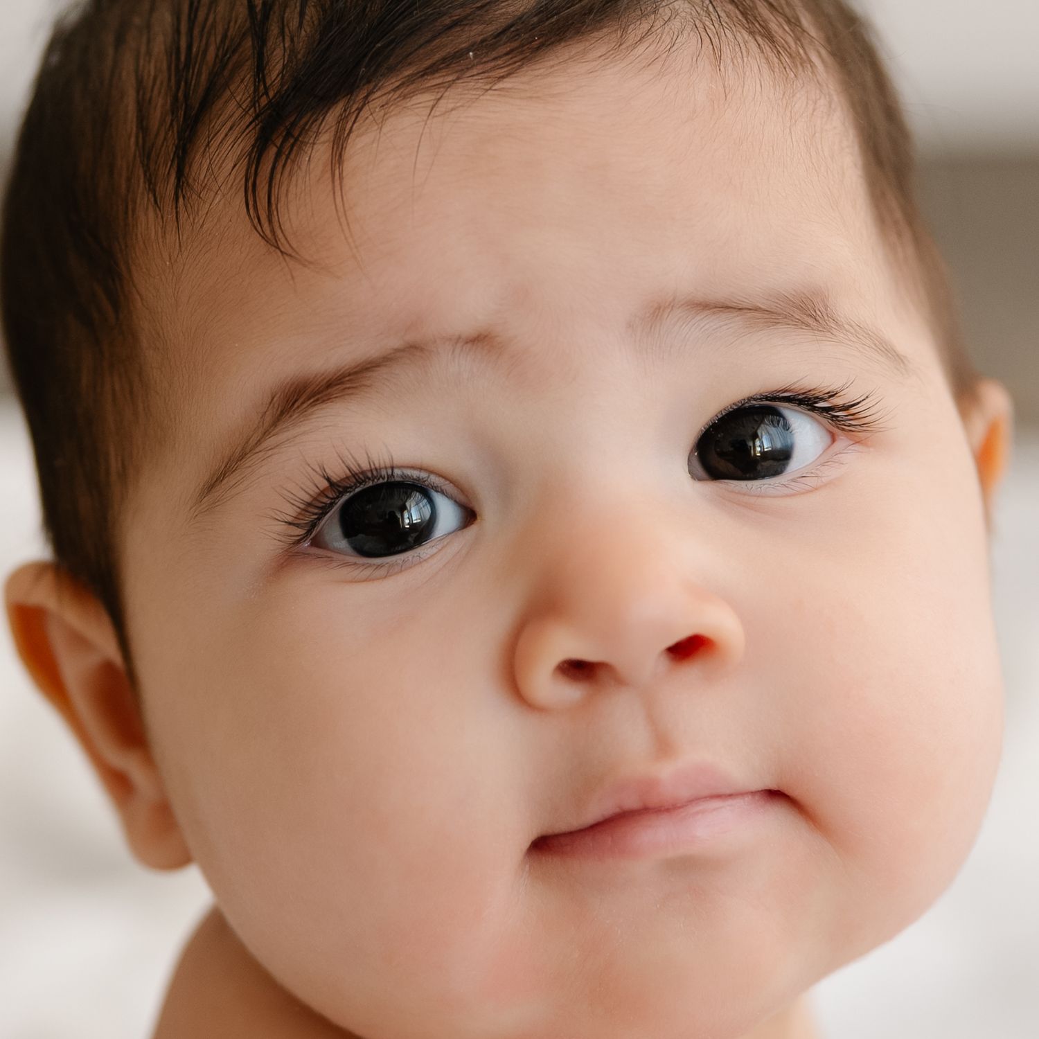 Close up portrait of a baby with big dark eyes looking directly at the camera.