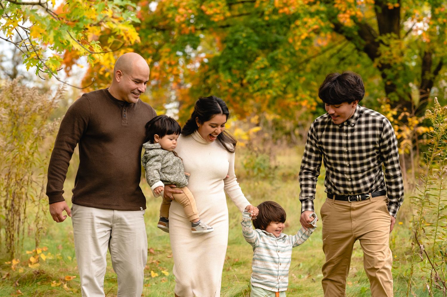 A group walks together through a park with golden autumn leaves overhead.