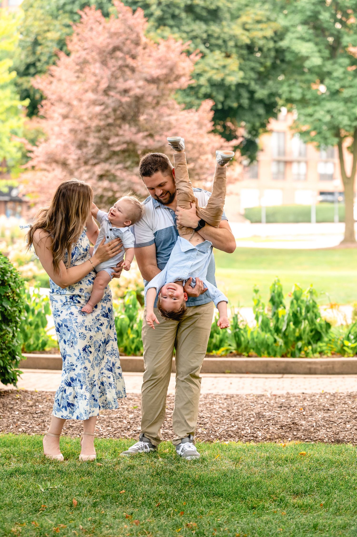 Family sharing playful moments together in park during summer photo session.