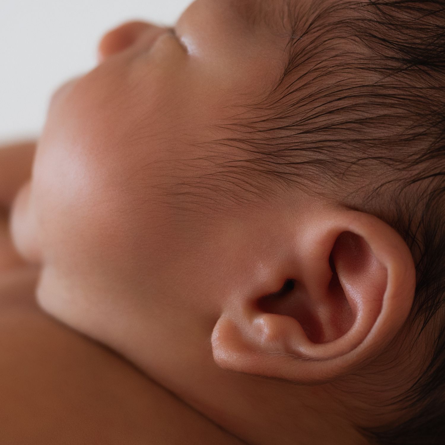 Close-up detail of a sleeping newborn's ear and soft skin.