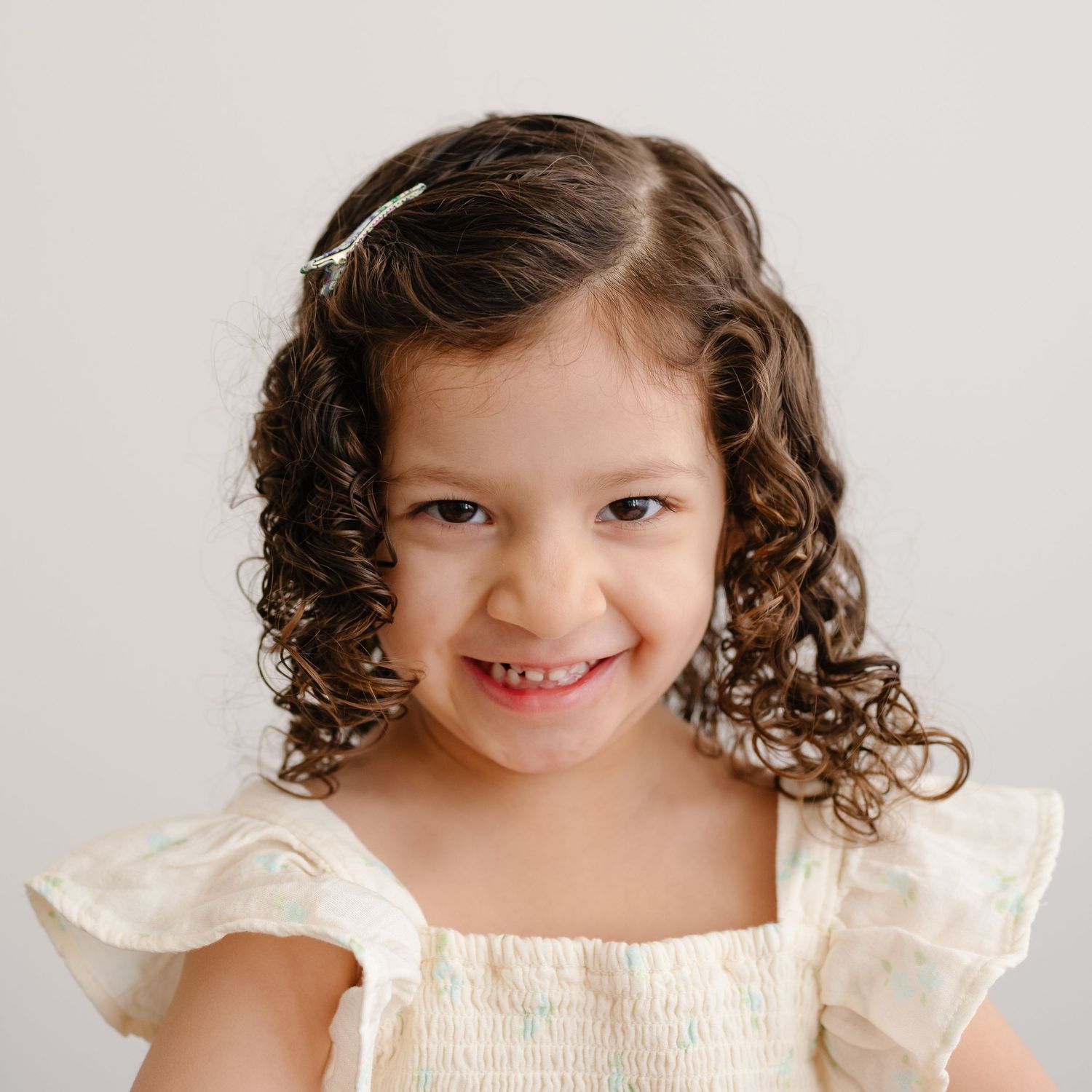 Portrait series showing sweet expressions and curly hair in cream colored dress.