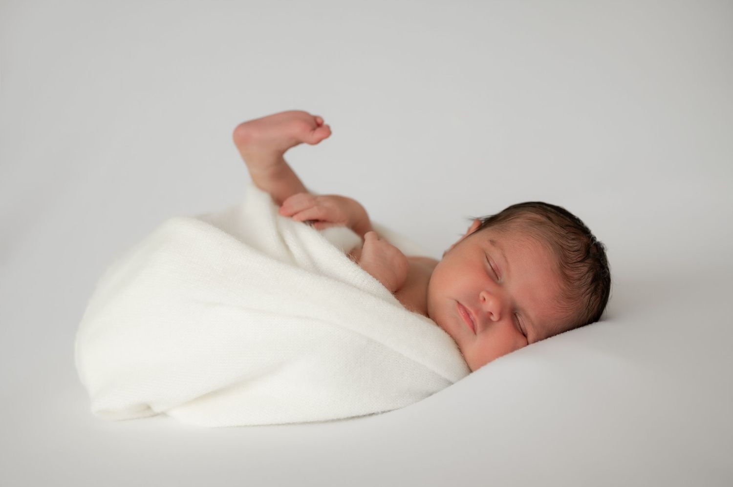 Newborn sleeping in a white wrap