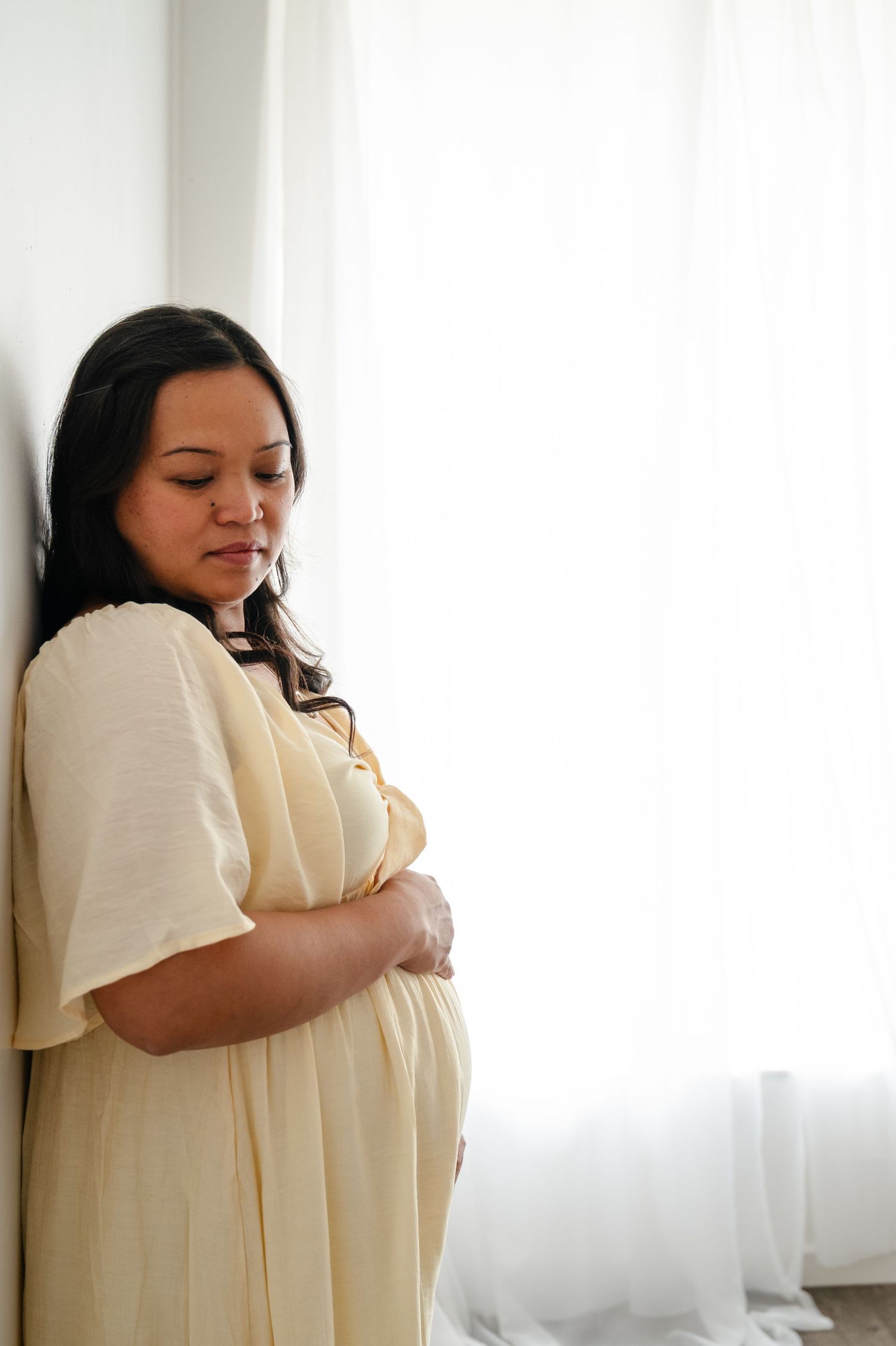 An intimate maternity portrait session captured in soft natural window light.