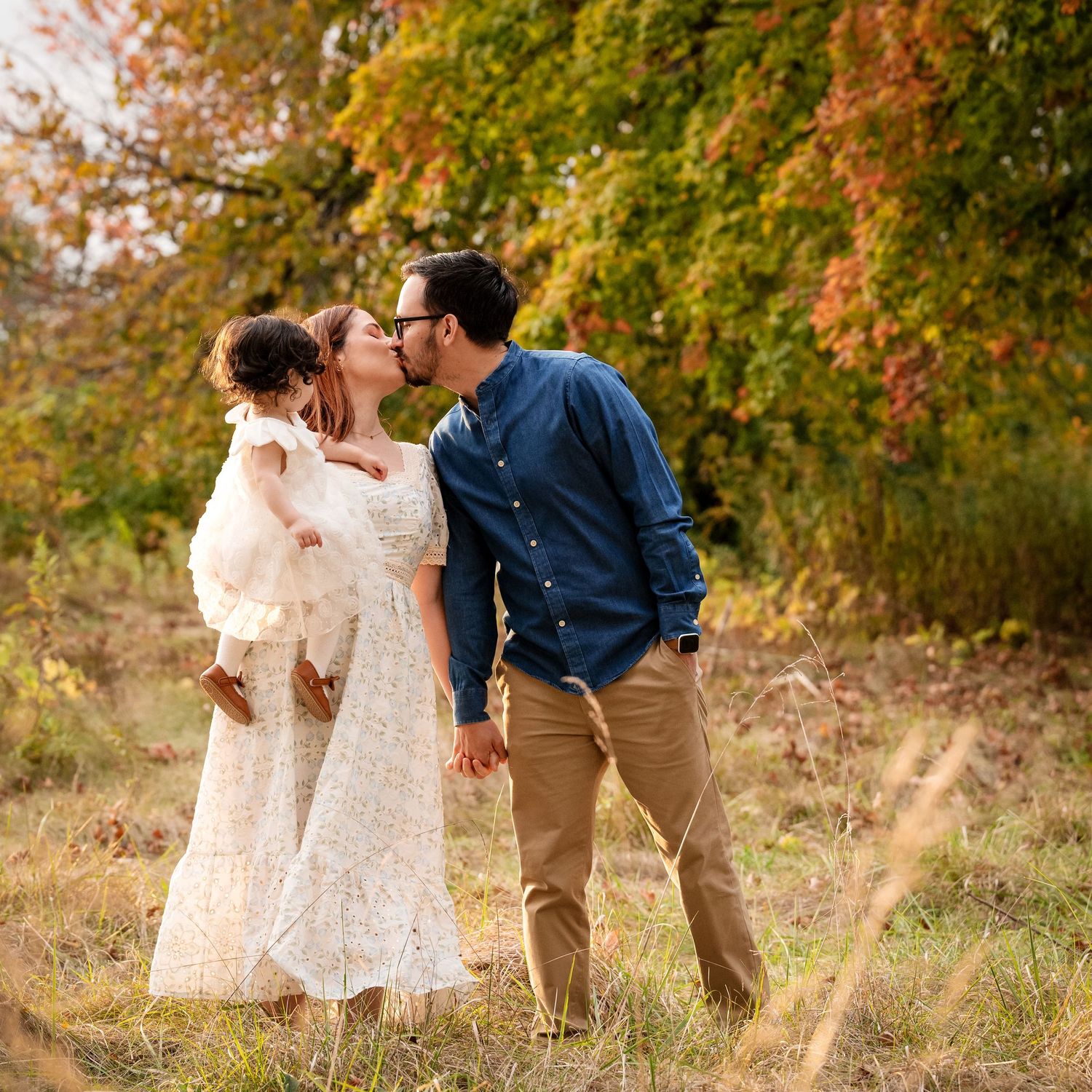 A couple shares a tender moment in a field during autumn.
