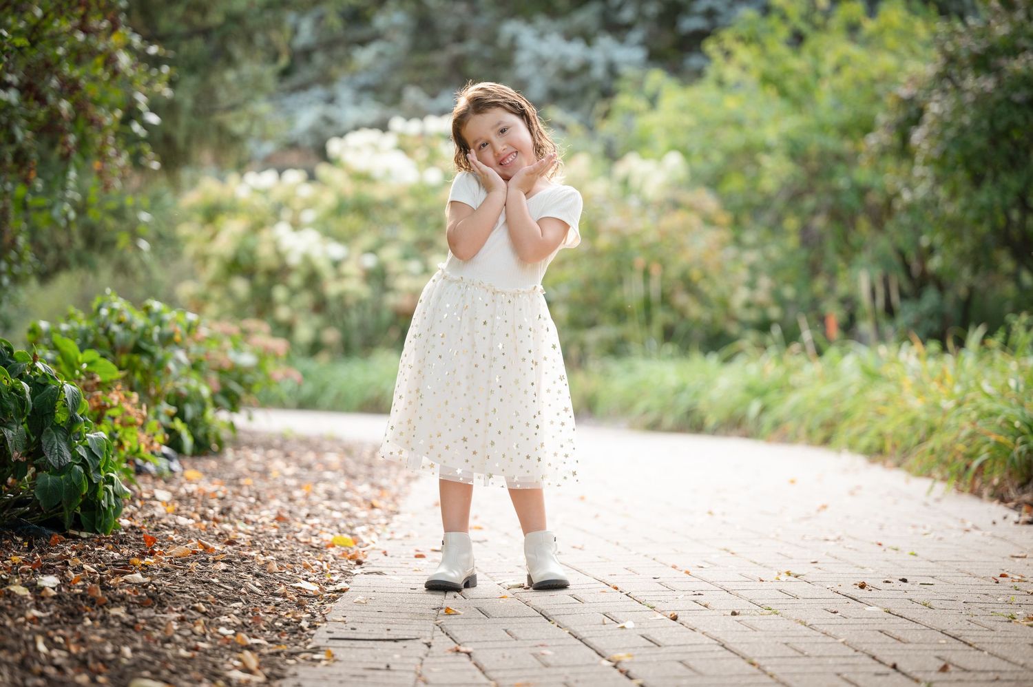 Children walking and playing on garden path surrounded by lush greenery.