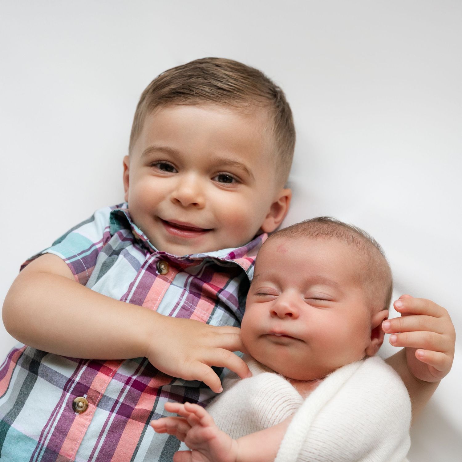 Two siblings sharing sweet moments against white background.