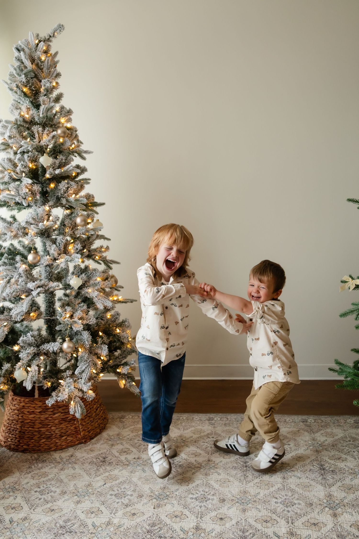 Children playing and dancing together by decorated Christmas tree during holiday photoshoot.