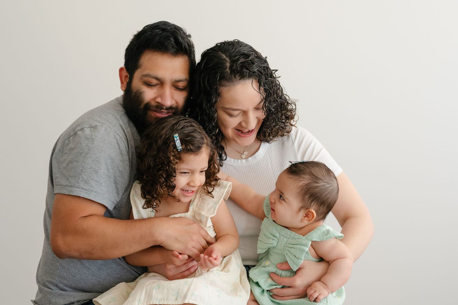 Family photoshoot against white background showing tender moments of togetherness.