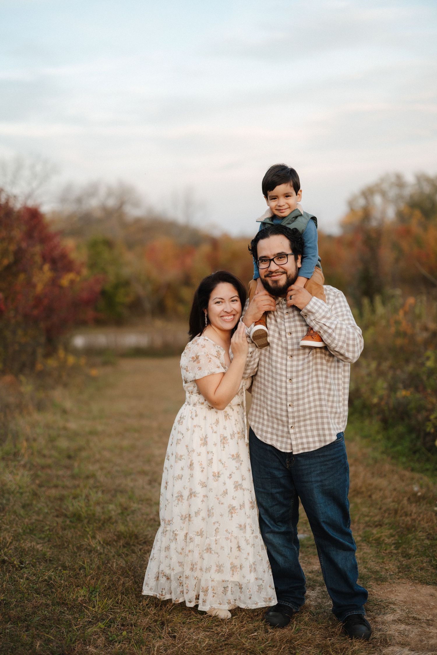 A loving family portrait session in an autumn field with fall foliage.