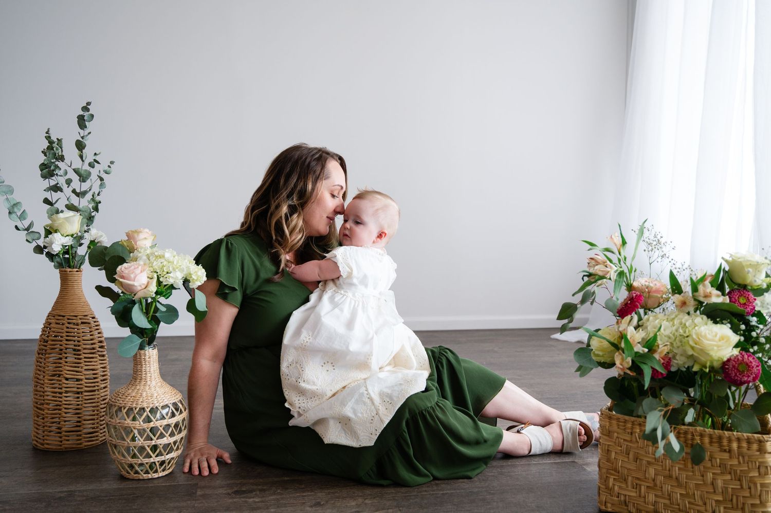 A heartwarming portrait with floral decorations featuring two figures in green and white outfits.