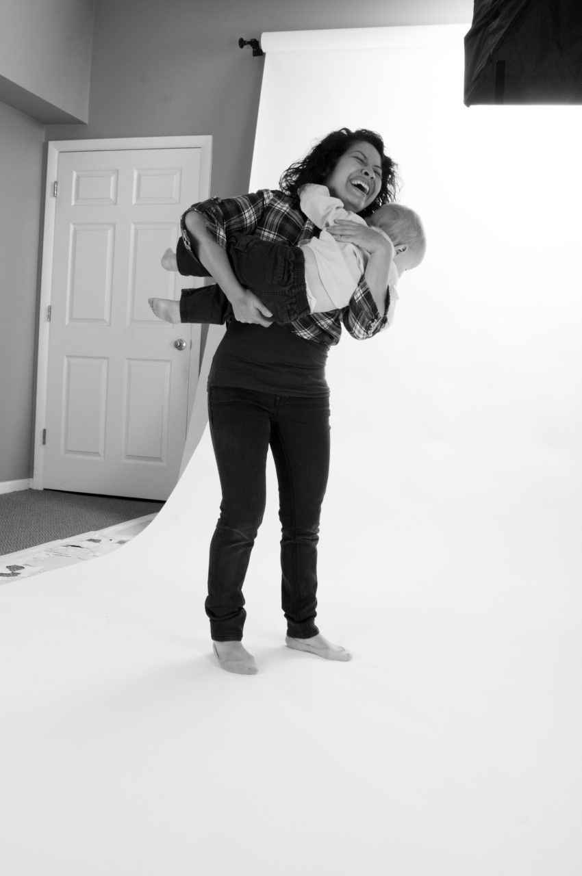A playful black and white photo of someone holding a child in a photography studio.