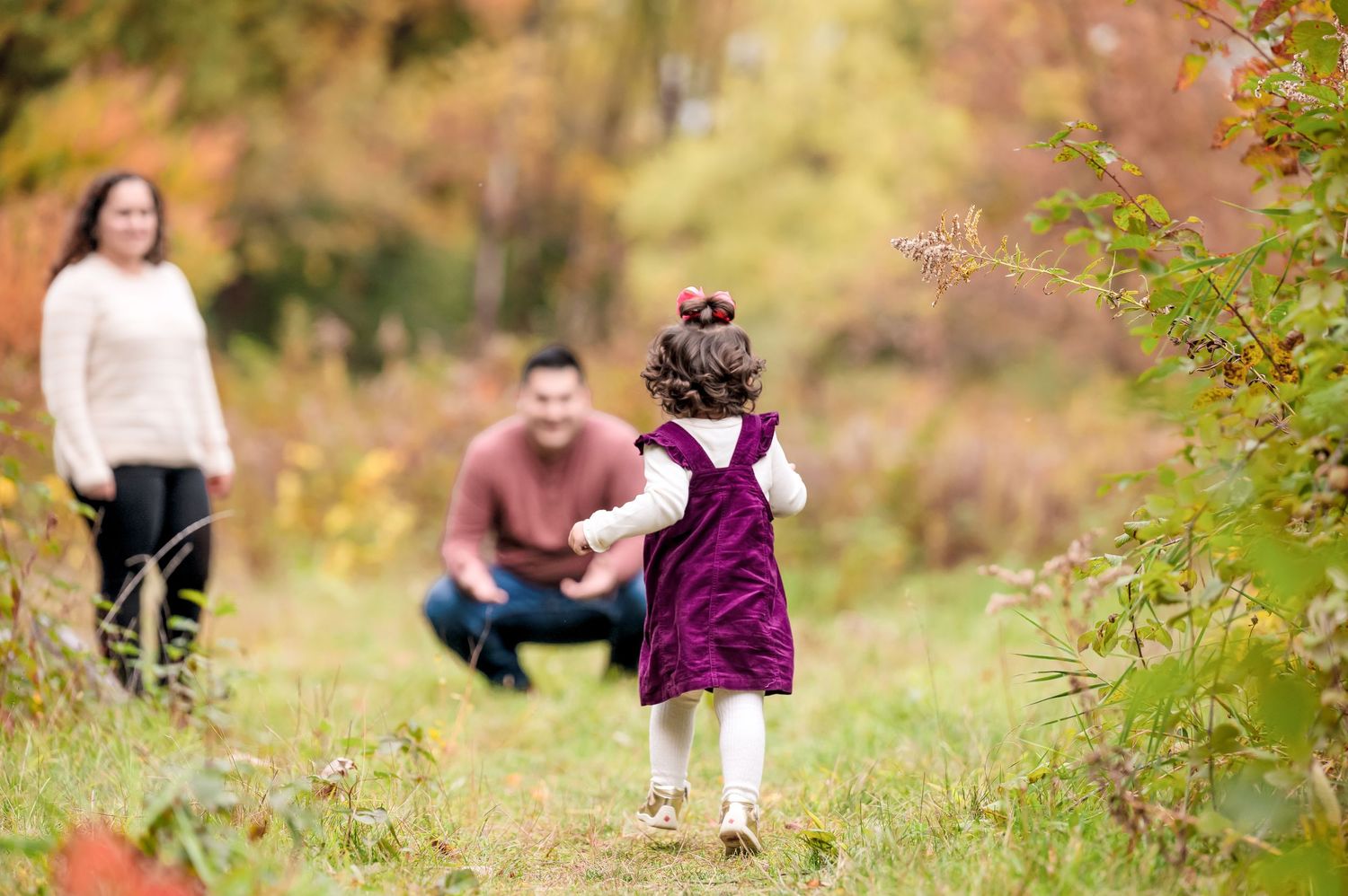 Young child runs to her parents in this fall scene.