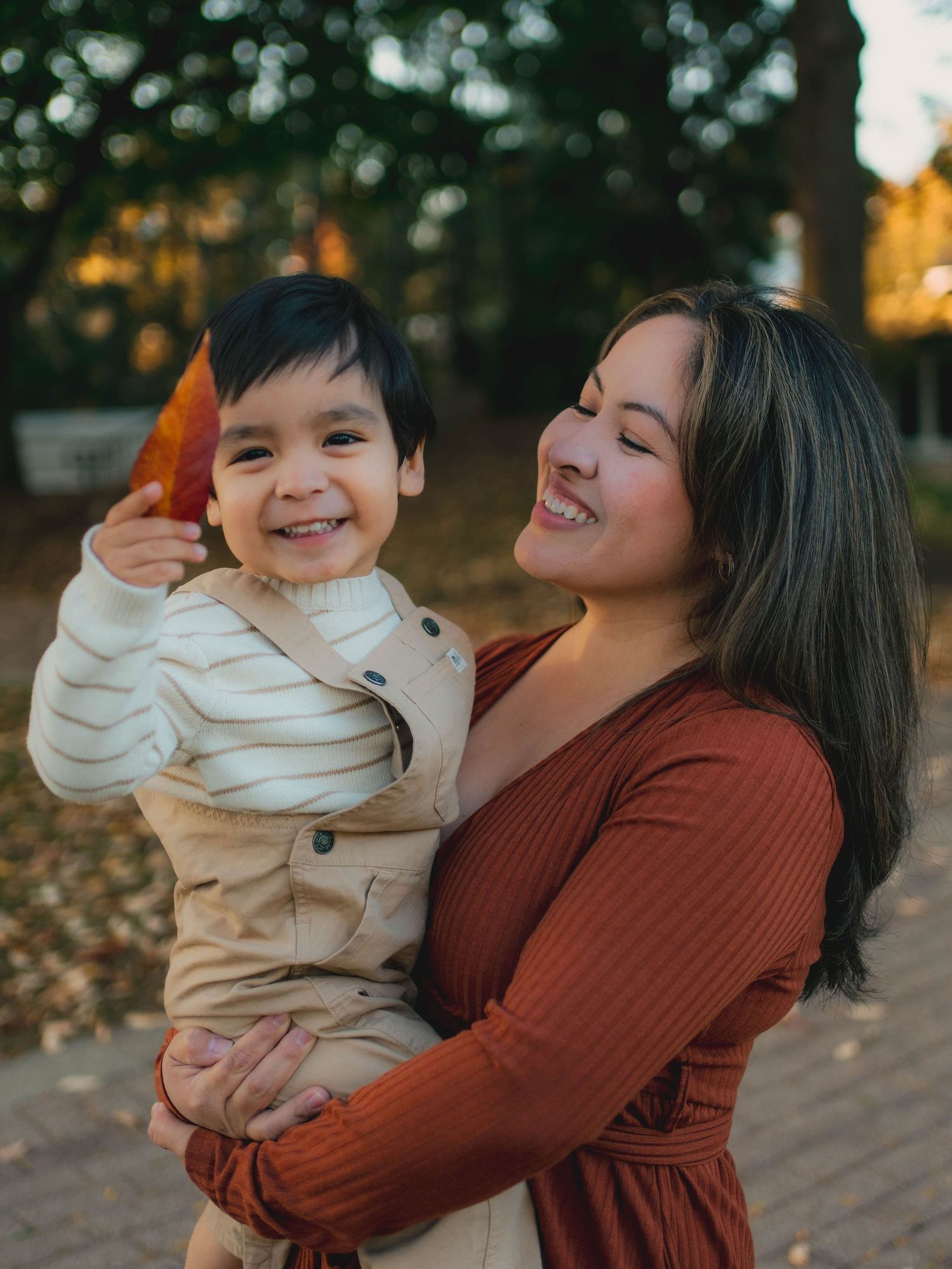 A parent and child share joyful moments together outdoors during an autumn photoshoot.