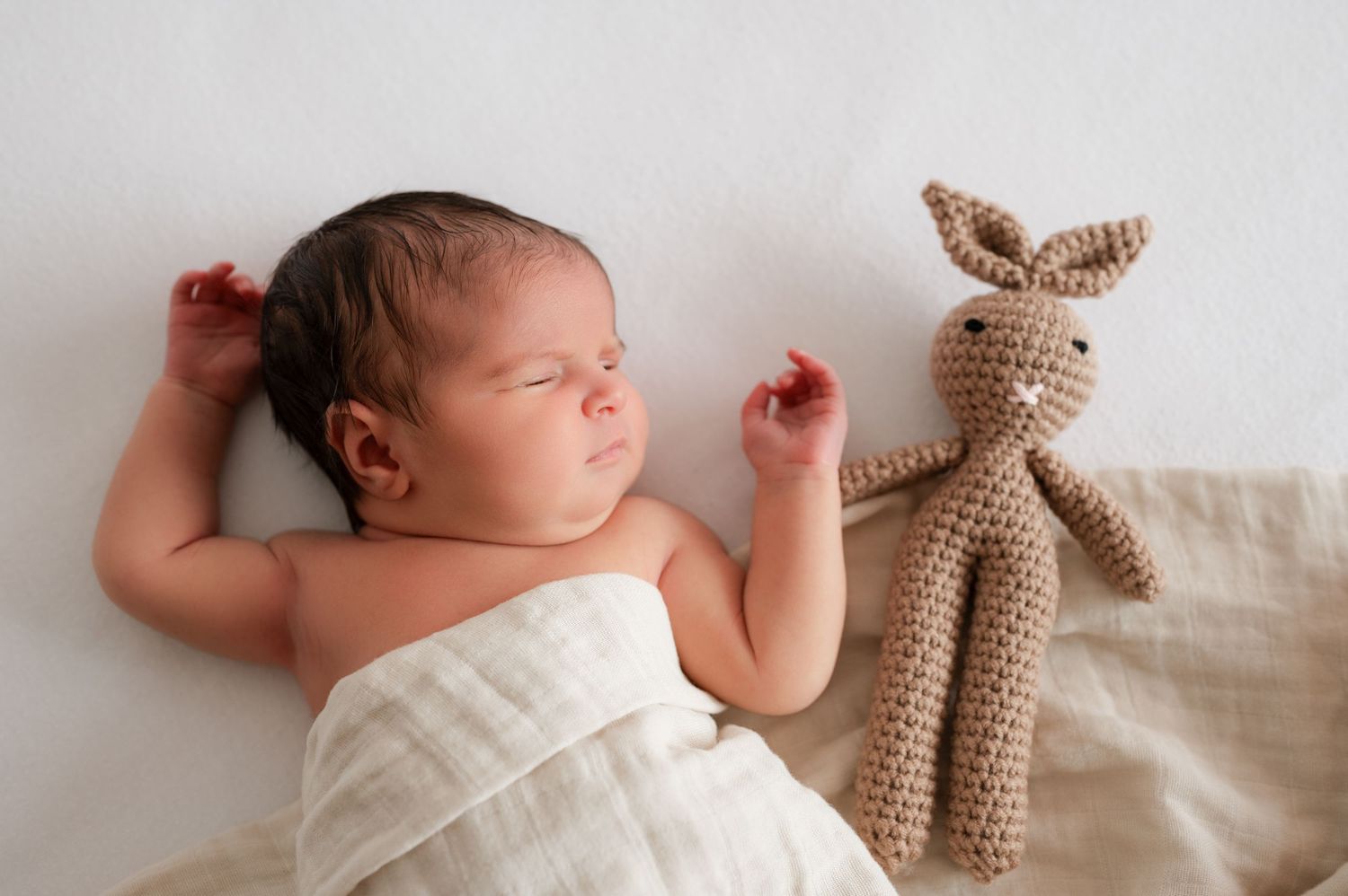 Newborn sleeping with stuffed bunny next to her.