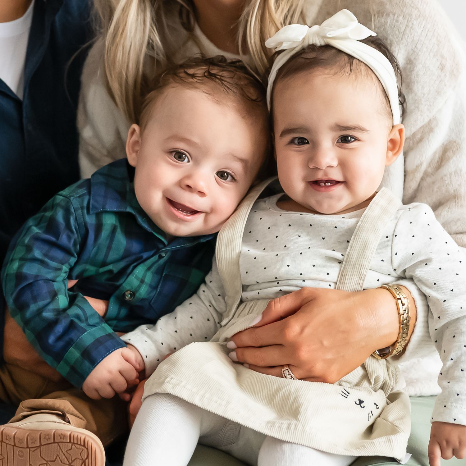 Two young children in coordinating outfits smile while sitting together.