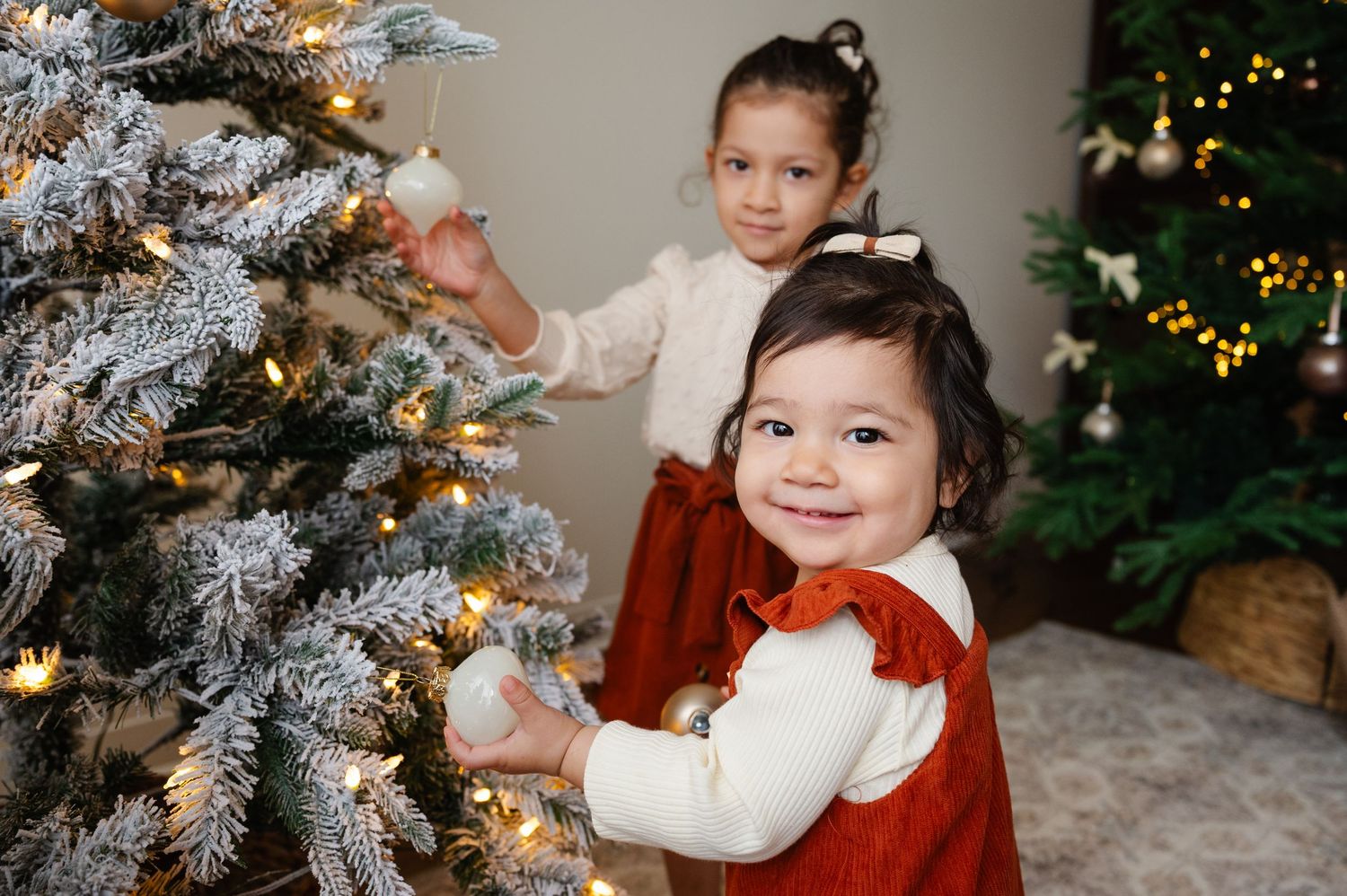 Children in festive holiday outfits pose near decorated Christmas tree.