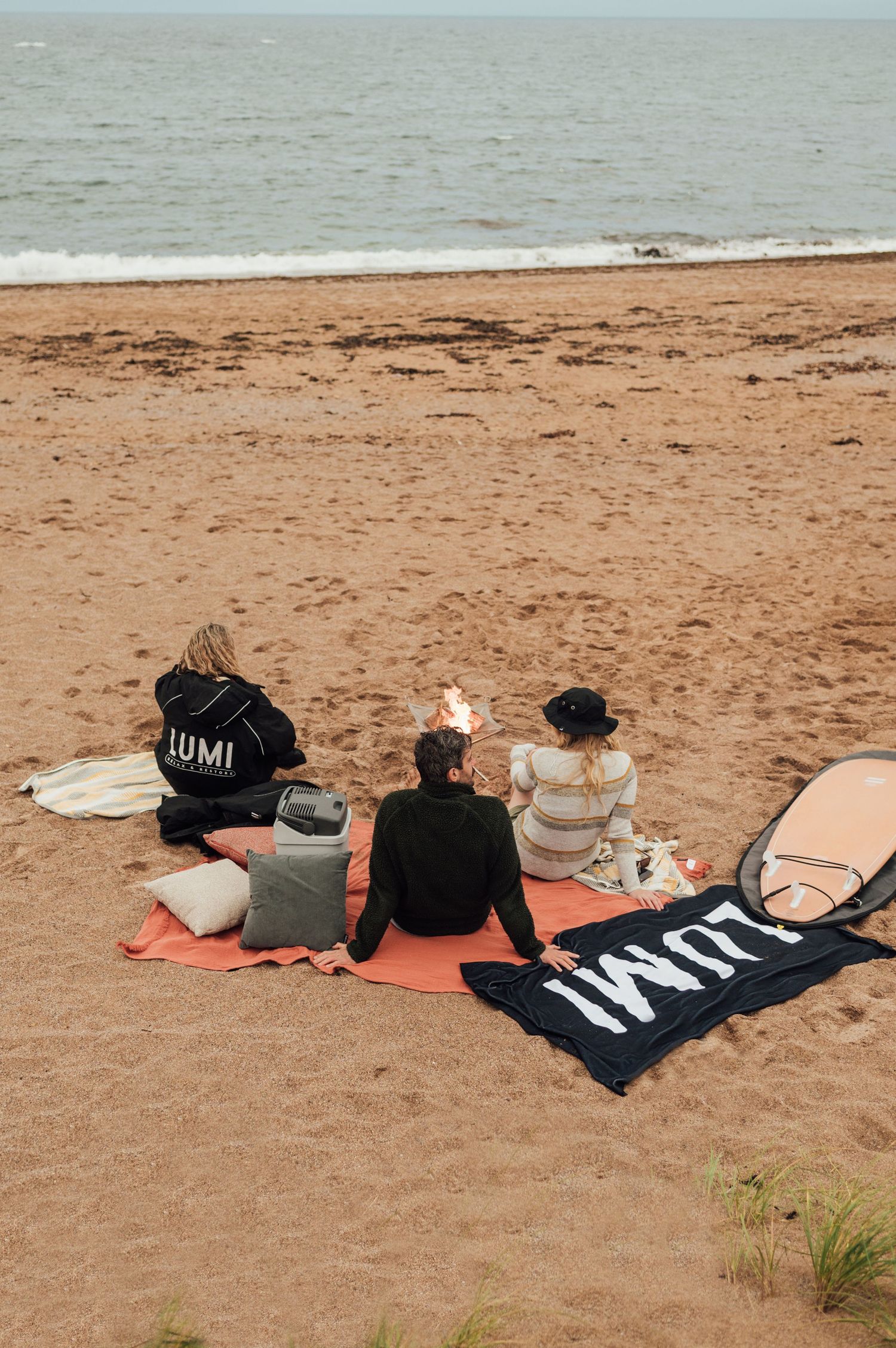 Three friends sitting on beach blankets watching the ocean waves.