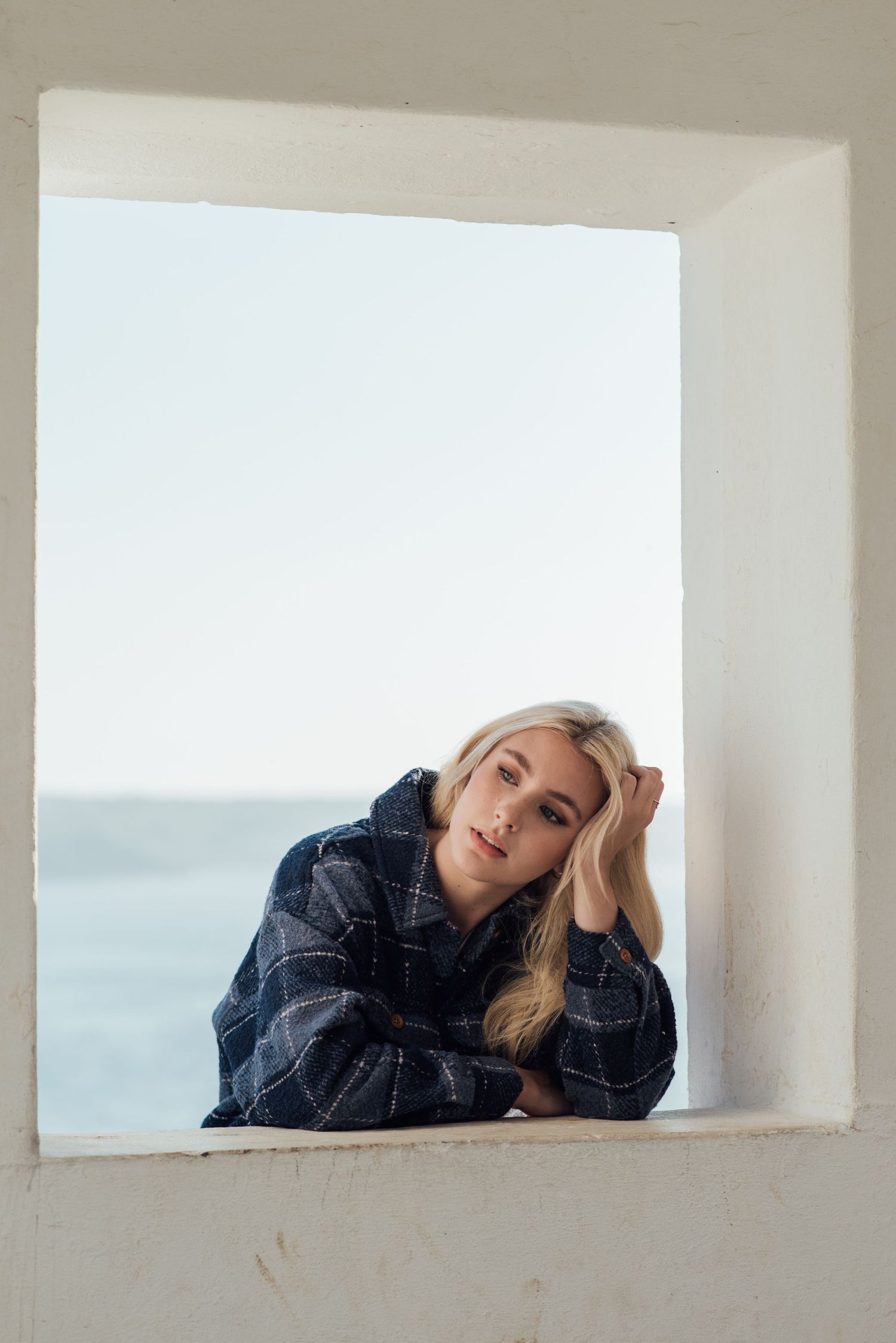 Artistic portrait through a white window frame overlooking the ocean.