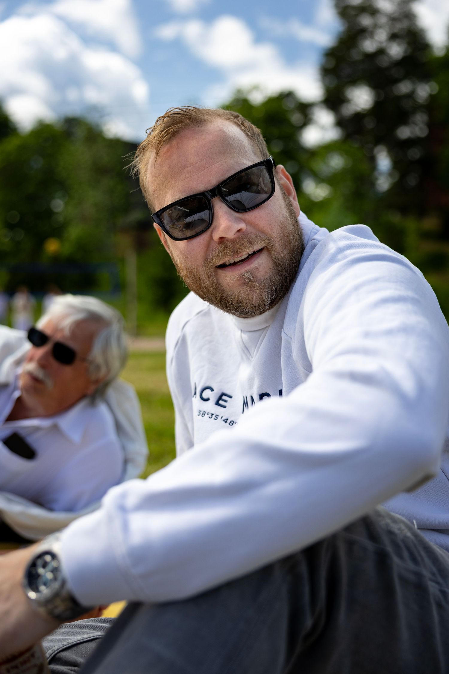 Person i vit hoodie och solglasögon avkopplande utomhus på solig dag.