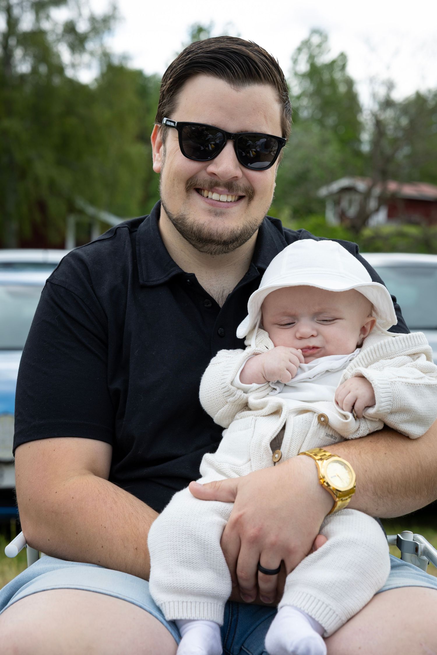 Förälder och barn i vit kläder delar stund utomhus en solig dag.